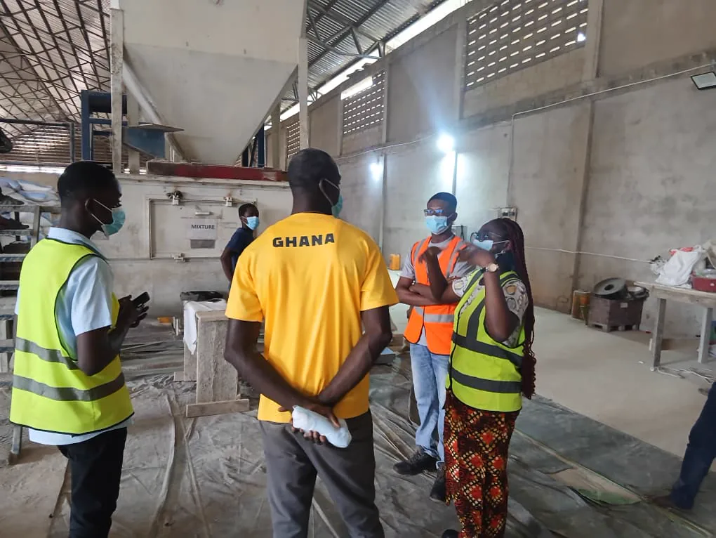 Kuapa Dwaso representatives speaking with warehouse workers beside maize handling equipment
