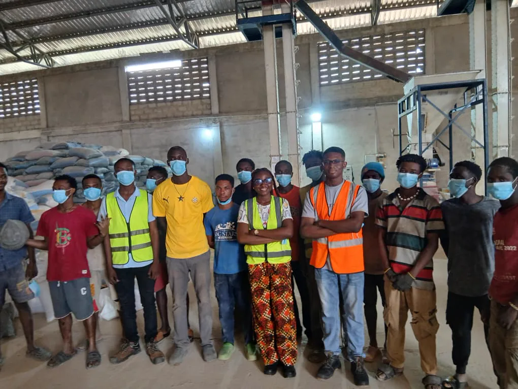 Extech staff and Kuapa Dwaso representatives gathered between stored maize and warehouse equipment