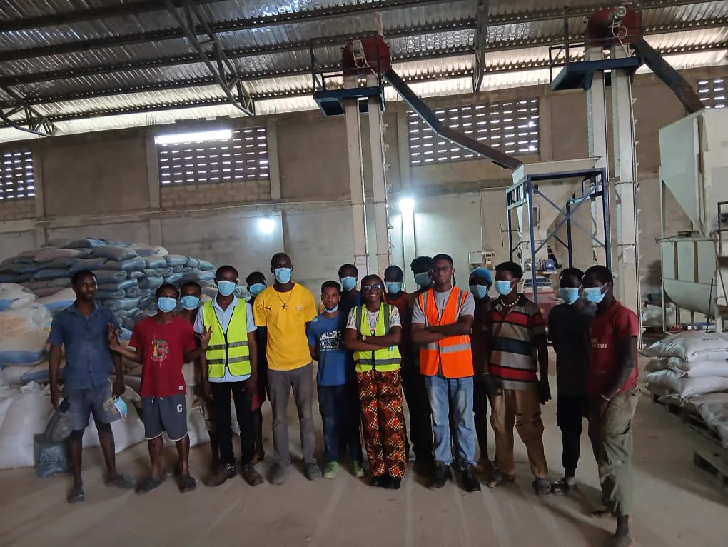 A wide group photograph of Extech staff, workers, and Kuapa Dwaso representatives in the warehouse