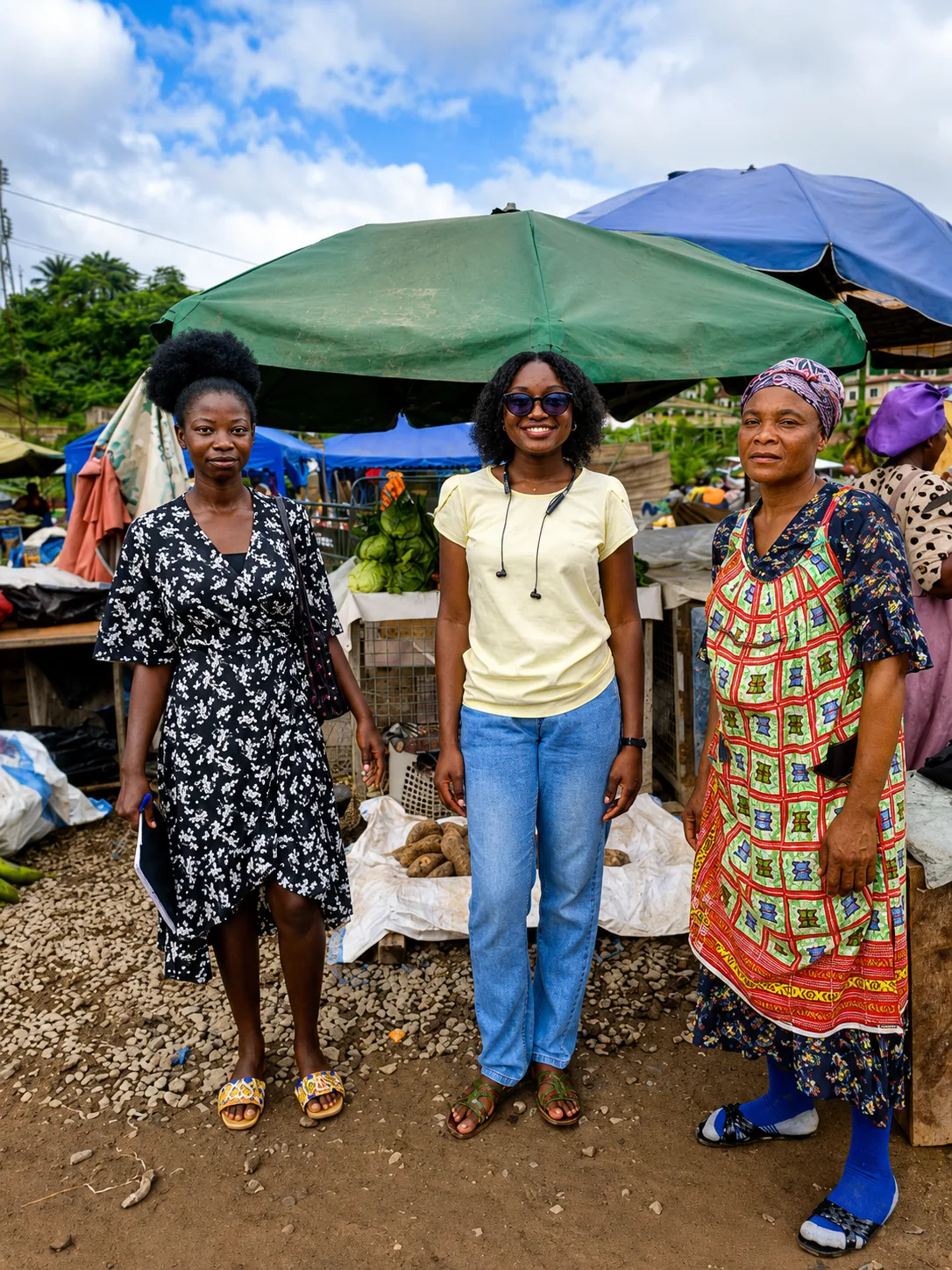 Two Kuapa Dwaso team members standing with a trader under market umbrellas in Tarkwa